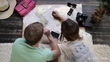 顶视图的潮夫妇躺在地板上在家里和计划假期旅行使用刮旅行地图